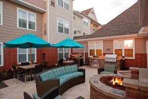 大急流城Residence Inn by Marriott Grand Rapids West的一个带两把蓝色遮阳伞和火坑的庭院