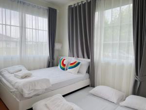 Ban Sathani Bandai MaHamilton House的白色卧室配有带枕头的床和窗户