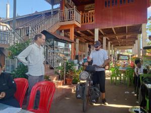 Krong KrachehTonle Mekong Homestay的两个人站在一座建筑物前面,拿着一辆自行车