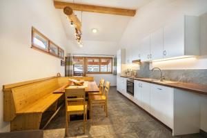 费尔代斯Seppnerhof Ferienwohnung Edelweiss的厨房配有白色橱柜和木桌