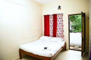 蓬蒂切里‌‌Florence guest house的一间卧室配有一张带红色窗帘和镜子的床