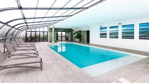 滨海迪沃Kyriad Prestige Residence & Spa Cabourg-Dives-sur-Mer的一座带躺椅的建筑内的游泳池