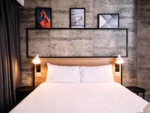 贝尔法斯特宜必思贝尔法斯特市中心酒店的一间卧室配有一张床,墙上挂着一些图片