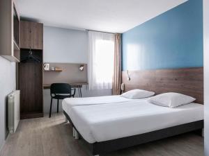 马西约HOTEL Lyon Nord Massieux Genay的配有一张床和一张书桌的酒店客房
