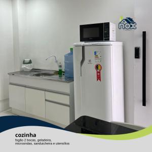 卡鲁阿鲁Nox Temporada - Flat 201 a 4km da Feira e Shopping Caruaru的小厨房配有冰箱上方的微波炉