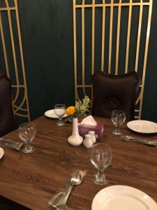 卡拉尔哥特RT Grace Royal Taj Hotel Sukkur的一张木桌,上面放有盘子和酒杯