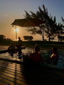 拉古纳Lagoon Suites e Gastronomia的一群人坐在游泳池里,日落时分