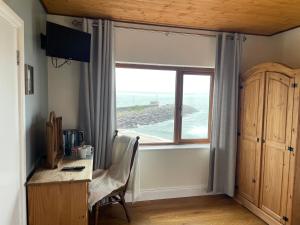 BallydavidThe Coastguard House @ Tigh T.P.的客房设有书桌和海景窗户。
