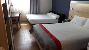 马拉加Holiday Inn Express Málaga Airport, an IHG Hotel的酒店客房设有两张床和一张桌子。