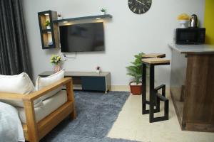 BungomaENz Lovely Apartment 8的客厅配有沙发和墙上的电视