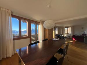 贝阿滕贝格Chalet Friesli Beatenberg的用餐室设有一张大木桌和窗户。