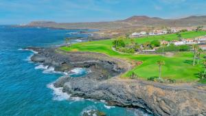圣米格尔德阿沃纳Amarilla Golf Suite by VV Canary Ocean Homes的享有毗邻大海的高尔夫球场的空中景致