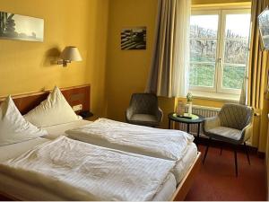 巴登-巴登温伯格餐厅酒店的酒店客房设有一张床、两把椅子和一扇窗户。
