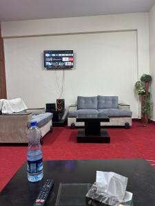 伊斯兰堡Islamabad lodges apartment suite的客厅配有沙发和桌子上的一瓶水