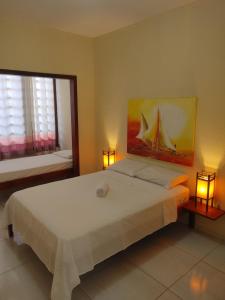 帕拉库鲁Pousada Viva Praia的一间卧室配有一张带两盏灯的大型白色床。