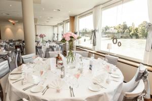 莱茵费尔登斯池艾瑞酒店的用餐室配有白色的桌椅和鲜花