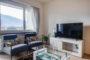 洛迦诺RELAX Ortensia Apartment的客厅配有2把椅子和平面电视