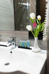 敖德萨Ribas Rooms Odesa的浴室水槽,花瓶上放着鲜花