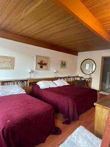 埃斯克尔Hosteria La Chacra的一间卧室设有两张红色床单和木制天花板