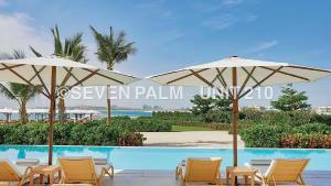 迪拜Luxus-Studio mit Private Beach in Top-Lage, Meerblick & Infinity Pool!的一组椅子和遮阳伞,位于游泳池旁