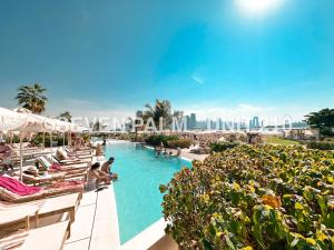 迪拜Luxus-Studio mit Private Beach in Top-Lage, Meerblick & Infinity Pool!的度假村的游泳池,人们坐在椅子上