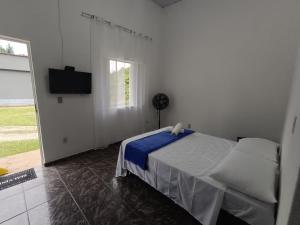 米格尔-佩雷拉Pousada Styllus Miguel Pereira的一间白色卧室,配有床和电视
