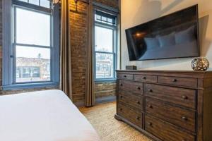 西邓迪Hip Urban Loft - Small Town Charm - 124 LOFTS #1的一间卧室配有一张床,梳妆台上配有电视