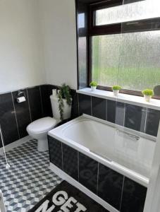 沃灵顿Charming 2-BR Property - Sleeps 5的带浴缸、卫生间和窗户的浴室