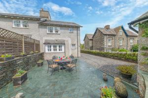 科尼斯顿Springbank Cottage, luxury Lake District cottage in Coniston的房屋前设有带桌椅的天井。