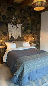波特雷里约斯Denmoza Eco Lodge的卧室配有一张石墙内的大床