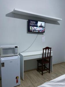伊塔皮拉Quarto privativo no centro 01的客房设有带微波炉的书桌和椅子。