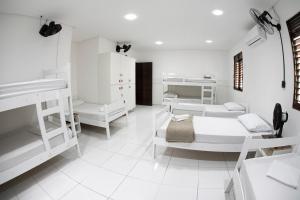 若昂佩索阿A Oca Hostel Bar的卧室设有白色双层床,铺有白色瓷砖地板。