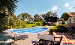 金巴亚Hotel Campestre Nogal de Cafetal的房屋旁的游泳池配有桌椅
