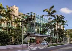 德尔雷比奇The Ray Hotel Delray Beach, Curio Collection By Hilton的一座拥有棕榈树玻璃幕墙的建筑