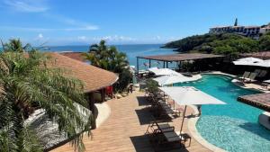 布希奥斯HOTEL VILLE LA PLAGE & BEACH CLUB的一个带遮阳伞和海洋的游泳池的度假酒店
