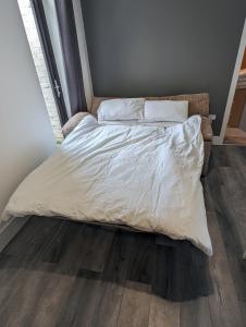 阿什顿-因马克菲尔德Station Apartments的卧室内的一张带白色床单和枕头的床