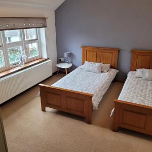 LlwyngwrilCosy modern cottage by the sea, heart of snowdonia的一间卧室设有两张床、一张桌子和两个窗户。