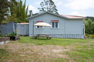 KaeoThe Farmhouse Kaeo Whangaroa的一个带野餐桌和雨伞的房子