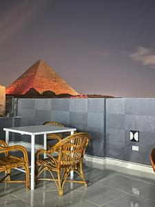 开罗Prince Pyramids Inn的一张桌子和椅子,后面是金字塔