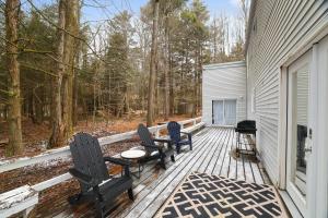 Pocono LakeCozy Pocono haven with lake access, hot tub, indoor & outdoor fireplace, games and pet friendly的门廊配有三把椅子、一张桌子和烤架