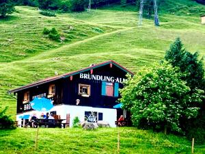 卑尔根Bründling-Alm Berggasthof auf 1167m auf dem Hochfelln的一座建筑,人们坐在外面,在山坡上