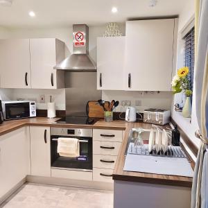 考文垂Impeccable 2-Bed House in Coventry的厨房配有白色橱柜和炉灶烤箱。
