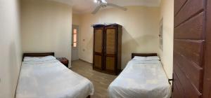 马特鲁港Almanara Hotel Marsa Matrouh的客房设有两张床和木制橱柜。