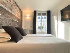 巴黎贝斯特韦斯特巴纳斯峰酒店的卧室配有一张白色大床和砖墙