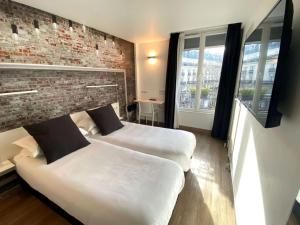巴黎贝斯特韦斯特巴纳斯峰酒店的砖墙旅馆客房的两张床