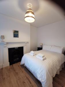 阿伯里斯特威斯Lovely Seafront 2 bed flat in Aberystwyth的卧室配有白色的床和壁炉