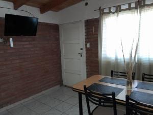 马拉圭El Pasaje的砖墙上的带桌子和电视的用餐室