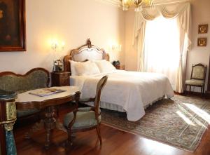 圣路易斯波托西Hotel Museo Palacio de San Agustin的一间卧室配有一张床、一张桌子和一个窗户。