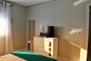 圣弗朗西斯科-迪保拉Apartamento da Júlio的卧室配有梳妆台,楼上配有电视