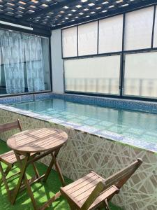 马斯喀特Al Hussam Hotel Apartments的一个带两把椅子和一张桌子的游泳池
